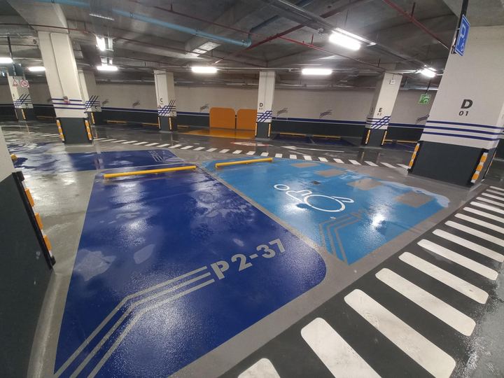 Kapalı otoparkta mavi zeminli engelli park yeri ve zebra yaya geçidi