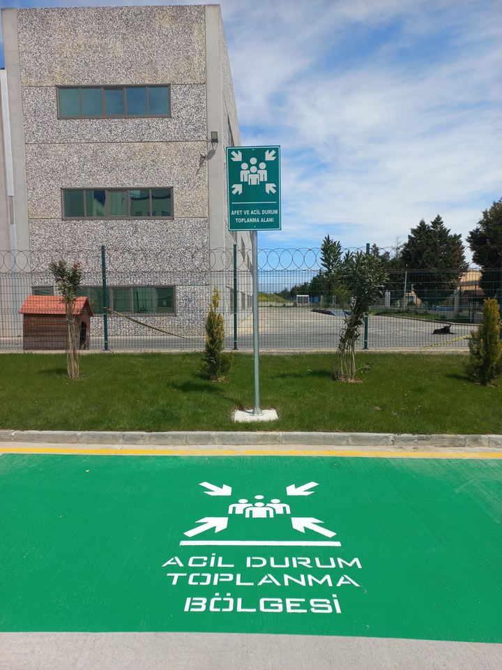 Yeşil zeminli acil durum toplanma bölgesi işaretlemesi