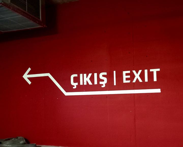 Kırmızı duvara beyaz Çıkış / Exit yazısı