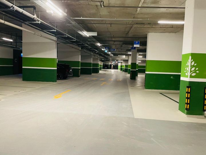 Yeşil kolonlu kapalı otopark koridoru ve sarı yön okları
